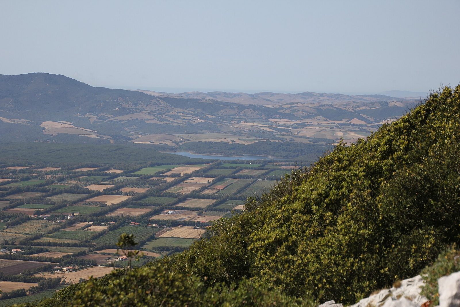 La pianura coltivata della Nurra e il lago di Baratz visti dall'alto, con le colline sullo sfondo